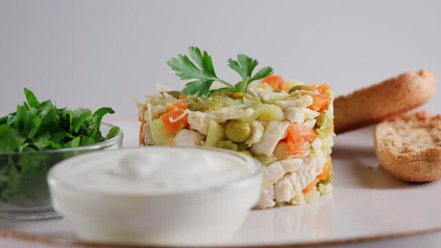 A healthy salad with chicken, boiled vegetables, eggs and canned peas served with homemade mayonnaise, chopped parsley and bread. High quality 4k footage