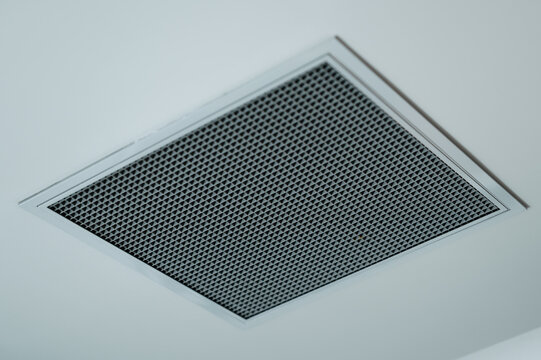 Low angle view of ceiling ventilation grille with geometric metal mesh on clean white indoor surface vent