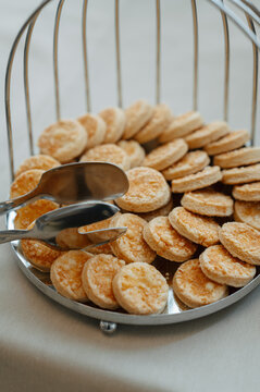 Round crackers sit in shiny serving tray beside metal tongs, creating inviting self-service snack display