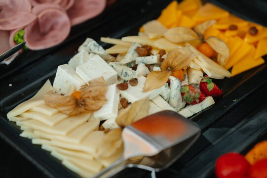 Assorted cheeses, berries, and fruit garnishes arranged on black tray for buffet service and tasting view