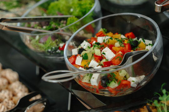 Mixed salad with diced peppers, cucumbers, feta cubes olives and parsley served in glass bowls on buffet