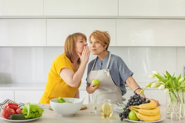 Mid adult  women gossip telling secrets and chatting while cooking in domestic kitchen at home © artmim