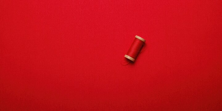 Textured red textile fabric featuring a red thread spool and blank copy space