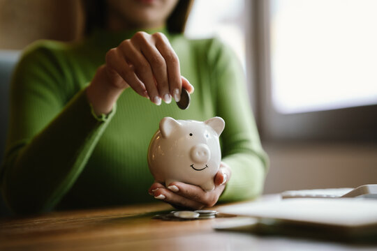 A close-up image of people dropping coins into a piggy bank, a symbol of saving and future financial security.