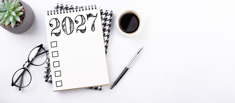 New year resolutions 2027 on desk. 2027 resolutions list with notebook, coffee cup on table. Goals, resolutions, plan, action, checklist concept. New Year 2027 template, copy space