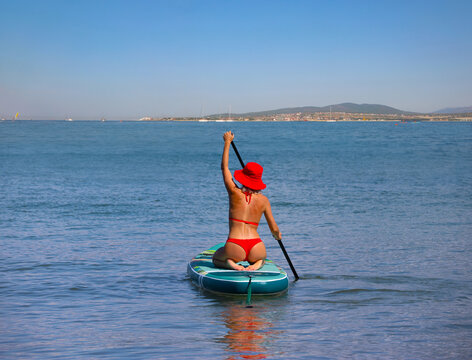 young women in red bikini  riding  on sup surfing in the sea at sumer time