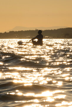 young women  riding  on sup surfing in the sea at sunset