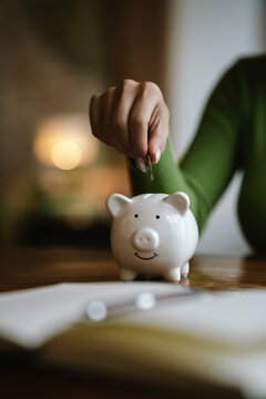 A close-up image of people dropping coins into a piggy bank, a symbol of saving and future financial security.