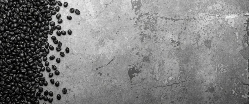 Black coffee beans scattered on a concrete surface