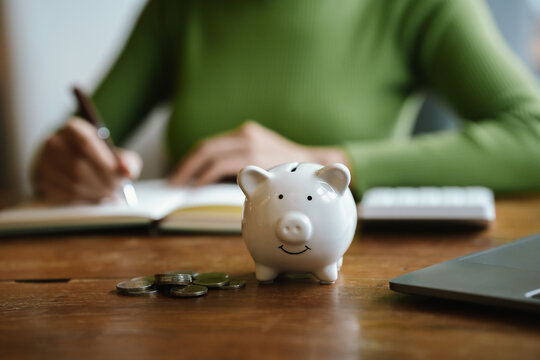 A close-up image of people dropping coins into a piggy bank, a symbol of saving and future financial security.