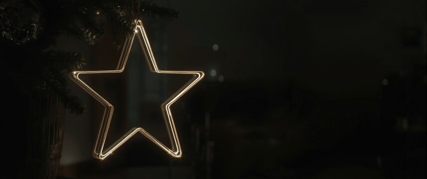 Illuminated star decoration hanging from a Christmas tree