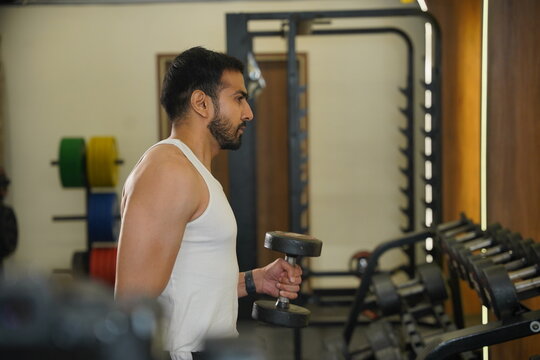 Maharashtra, Sion, India- 22nd March 2026- Young Indian guy doing workout With dumbbells in gym 