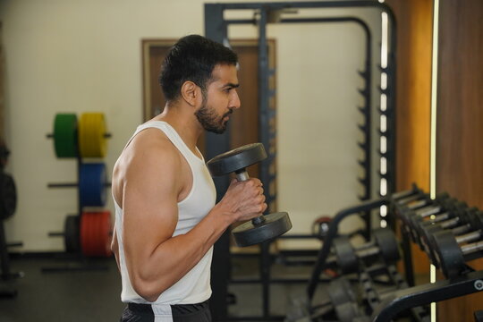 Maharashtra, Sion, India- 22nd March 2026- Young Indian guy doing workout With dumbbells in gym 