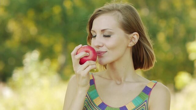 Young beautiful woman eating ripe red apple