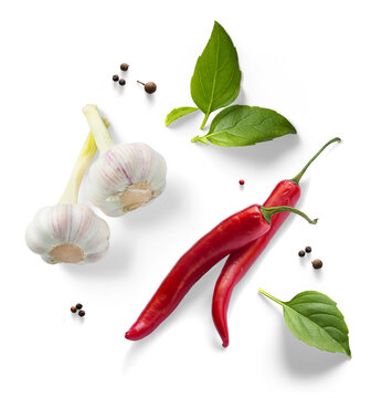 Spicy cooking ingredients composition with chili peppers, garlic, basil and spices isolated on white background, culinary food preparation set for recipe and kitchen design