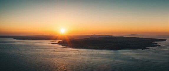 Obraz premium Sunrise over an island and calm sea waters