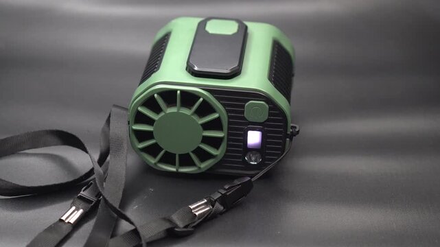 A green tactical portable neck fan on a dark background.