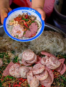 Traditional Vietnamese noodle bowl with local ham and sausages (Cha Hue) served by a street vendor.