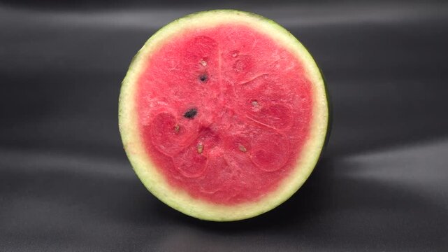 a freshly cut half watermelon on dark background.