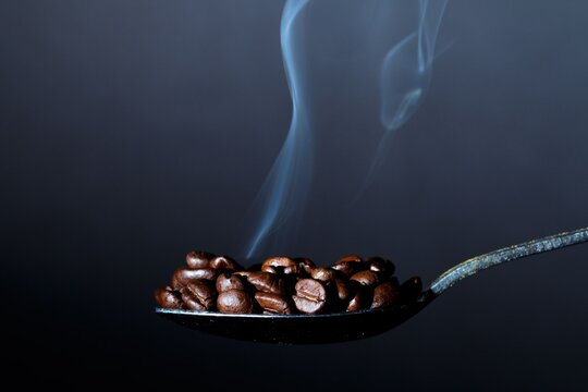 Freshly Roasted Coffee Beans on a Spoon with Rising Smoke Wisp