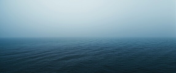 Obraz premium Still ocean waves under a hazy blue sky