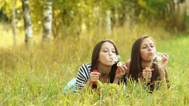 Two beautiful young women inflate soap bubbles