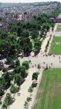 Bastille Day top-down aerial Champ de Mars Paris, Eiffel Tower foot shadow on grass, formal geometric park, bird's eye view, cinematic France July 14 drone b-roll