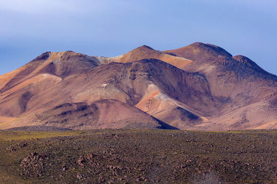 View of the volcanic landscape of Piedras Rojas with rugged mountain peaks, rocky terrain, and clear sky in the Atacama Desert, San Pedro de Atacama, Antofagasta, Chile.