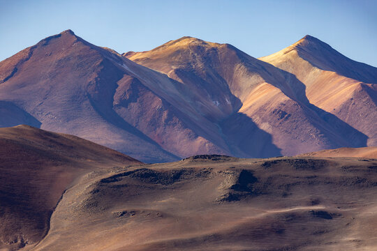 View of Piedras Rojas with rugged volcanic mountain peaks, dramatic shadows, and arid desert terrain in San Pedro de Atacama, Antofagasta, Chile.