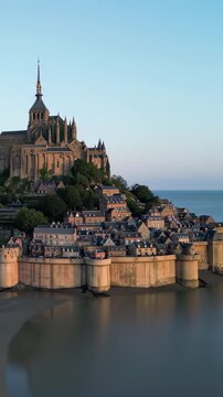 Bastille Day aerial Mont Saint-Michel island abbey, tidal flats, golden archangel spire, morning light, cinematic drone orbit, France July 14 national day landmark b-roll