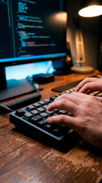 Software developer typing on backlit mechanical keyboard during late night coding session