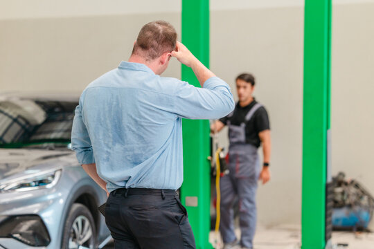 Frustrated customer talking on phone about expensive EV car repair at auto service center
