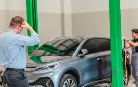 Frustrated customer talking on phone about expensive EV car repair at auto service center
