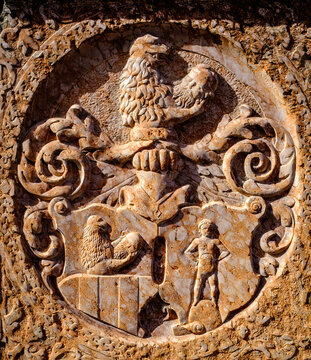 Historical carving of a sword and olive branch on stone wall in a public place during midday
