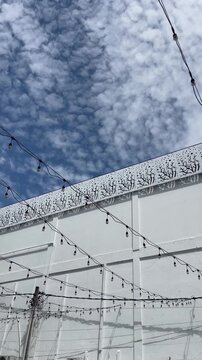 minimal outdoor string lights hanging across a modern frame under a textured cloudy sky, urban atmosphere, copy space, architectural detail