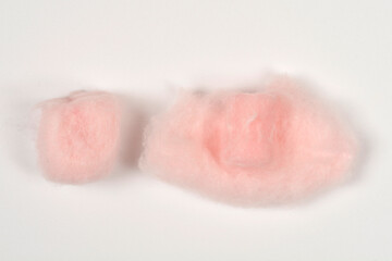 Fototapeta premium Top view of two soft pink wax earplugs wrapped in protective fluffy cotton wool fibers on a seamless white surface.