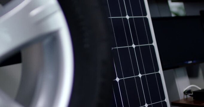 Close up pan shot of an alloy car wheel rim next to a solar panel