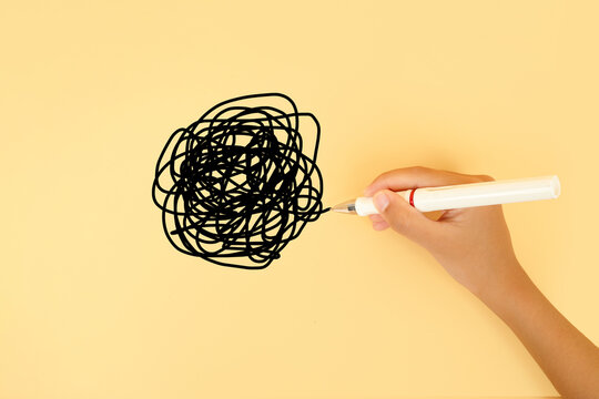 Hand drawing a tangled scribble on a pastel background. Concept of confusion, stress, overthinking, mental clutter, problem solving and chaotic thoughts.