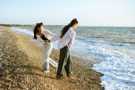 Teenager girls 15-16 year old having fun at beach walking in sea coast outdoors. Summer vacation time. Teenagerhood.
