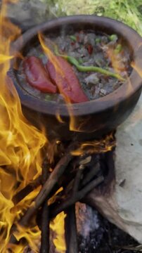 Outdoor bushcraft cooking with an earthen casserole on a wood fire in nature.