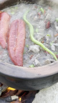 Authentic outdoor cooking of meat, fat, and vegetables over a roaring campfire.