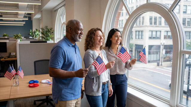 Diverse business team celebrating American Independence Day with flags by office window for corporate holiday communications and promotional materials