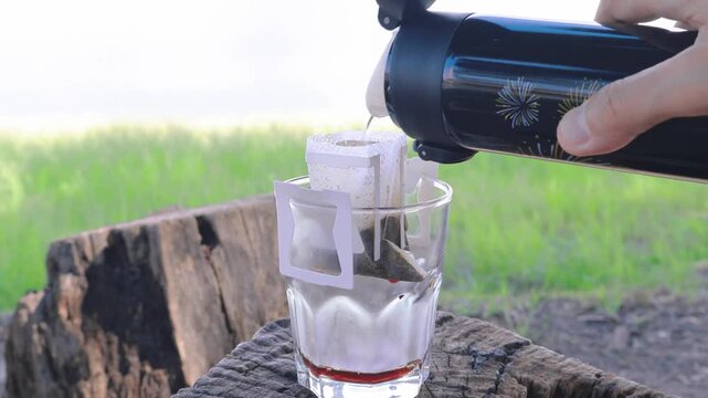 Portable Drip Coffee Being Poured Slowly with Hot Water at the Lakeshore Campsite