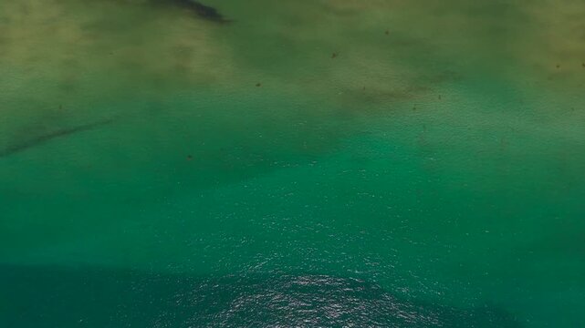 Title: Top down aerial view of turquoise ocean water with shallow sandbar texture
