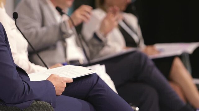 Business panel discussion with gesturing speaker and microphones at corporate conference, leadership forum and executive event. Round table political meeting. 