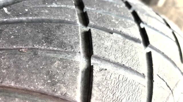 The tire tread is deteriorating and starting to show cracks on the surface.