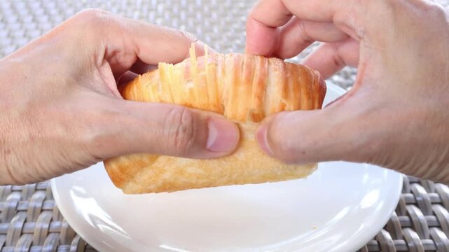 Close up of warm viennoiserie pastry pulling apart showing buttery laminated layers