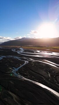 Vertical Drone Shot of sunrise light hitting Over Glacial Rivers in Stora Dimon, Iceland