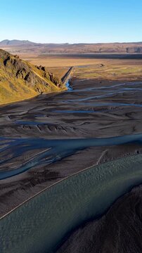 Vertical Aerial Drone Shot of Braided River Near Mountain Ridge at Stora Dimon, Iceland in a sunny day