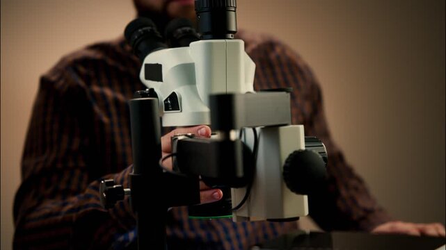 Electronics Technician Examining Circuit Board Under Stereo Microscope